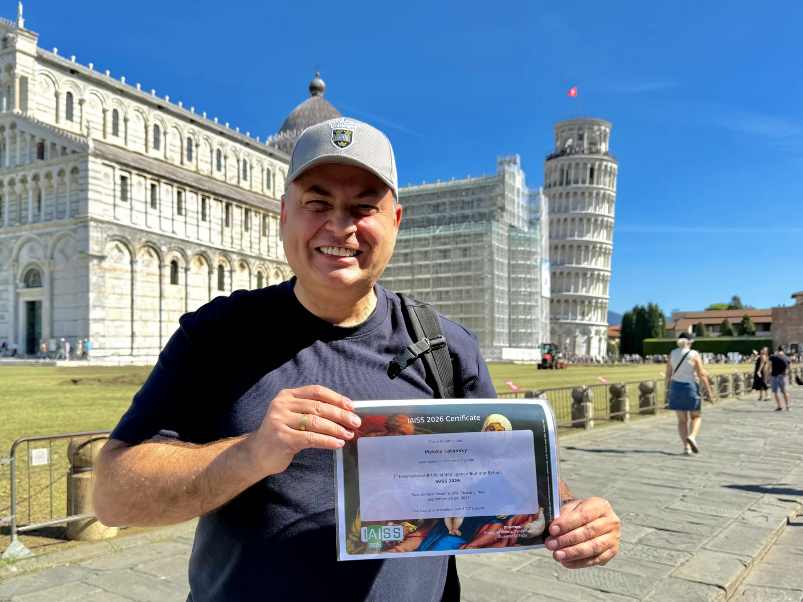 Mykola Latansky holding his IAISS 2026 certificate beside the Leaning Tower of Pisa