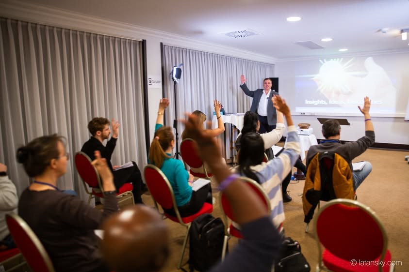 Participants raising their hands with Mykola Latansky at a learning event in Budapest