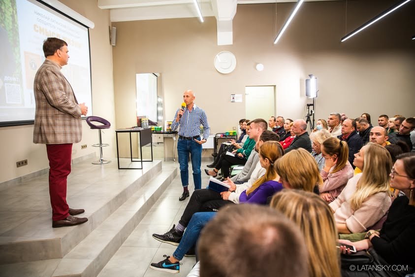 Mykola Latansky listening to a participant with a microphone in a filled Kyiv room