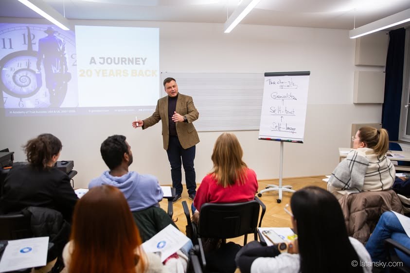 Mykola Latansky speaking beside a presentation screen in Vienna