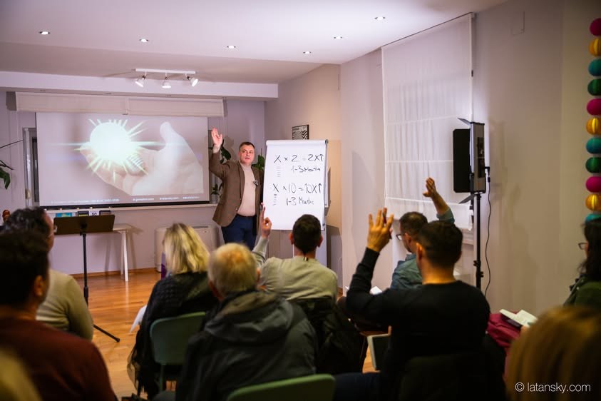 Mykola Latansky and participants raising their hands at a live learning event in Zagreb